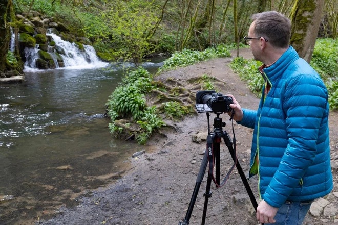 photographer taking a photo of a waterfall in the woods